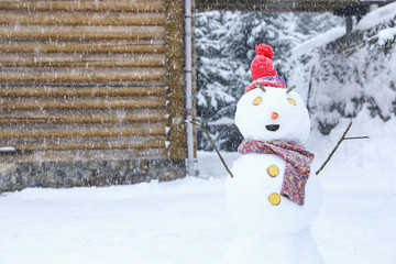 Funny snowman with hat and scarf outdoors on snowy day. Winter vacation