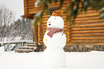 Funny snowman with hat and scarf outdoors. Winter vacation