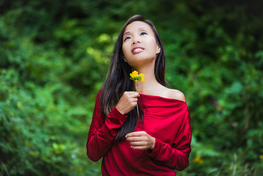 belle jeune femme asiatique avec une fleur, détente en extérieur 