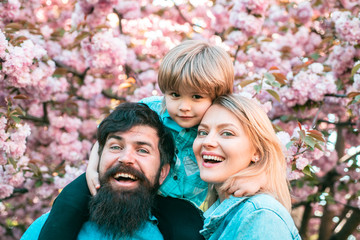 Portrait of happy family in blooming Garden. Spring time. Mother father and son.