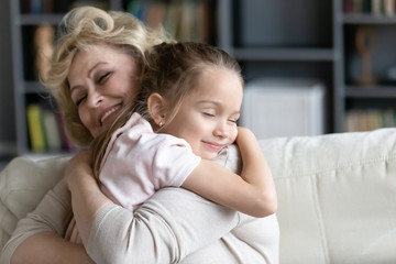 Happy senior granny cuddle with cute preschooler granddaughter