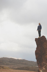 man standing on top of a high rock looking at the horizon