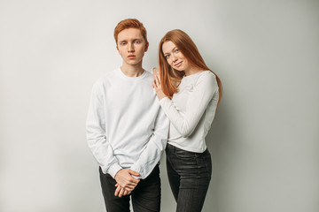 portrait of young gorgeous caucasian red haired brother and sister isolated over white background, unusual woman and boy in white shirt posing and looking at camera