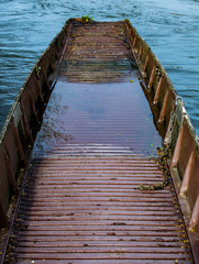 Brown abandoned row boat, vintage wodden boat sinking floating on the water.