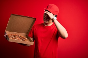 Young handsome chinese delivery man holding deliver box with delicious Italian pizza stressed with hand on head, shocked with shame and surprise face, angry and frustrated. Fear and upset for mistake.