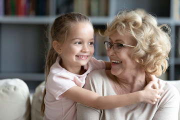 Happy elderly grandmother playing with little cute granddaughter