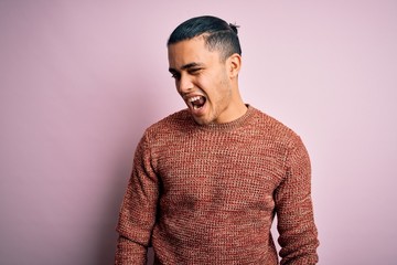 Young brazilian man wearing casual sweater standing over isolated pink background winking looking...