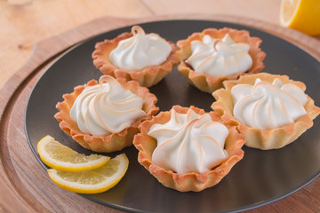 Lemon Tartlets with meringue on black plate. 