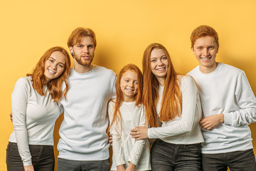 group of young, attractive smiling caucasian people with natural red hair gathered together in studio with yellow background.redhead day. rare type of people with natural red hair. people diversity