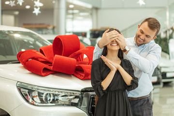 young handsome caucasian guy make surprise to brunette woman, going to give a gift. man closed...