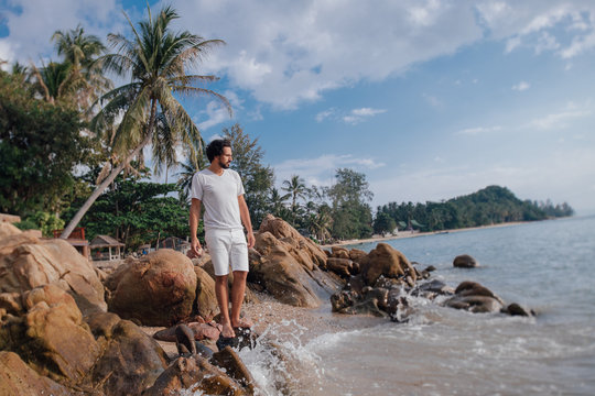 A man on the tropical coast in stones by the sea.