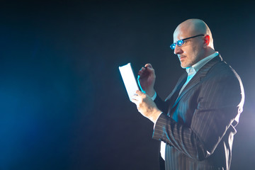 A man with glasses is holding a tablet and stylus. Technical gad © Grispb