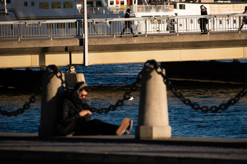 Out of focus man with headphones relaxing on a coastline harbor