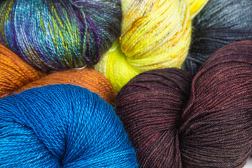 background of multicolored silk and merino wool skeins with yellow, green, blue, brown and purple