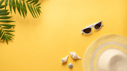 composition with beach accessories on a yellow background with green foliage. Beach travel concept. horizontal background with empty place for text.