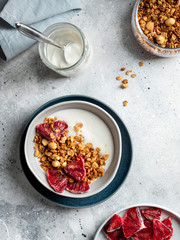 homemade granola, yogurt and bloody orange in a bowl on a gray concrete background. Healthy and fiber food. vertical image, copy space, top view.