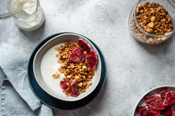 bowl with natural yogurt, granola and bloody orange on a gray concrete background. Clean eating. horizontal image, copy space, flat lay.
