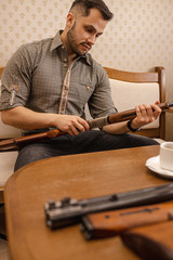 young caucasian man inspecting rifle in salon, he want to buy rifle for hunting. protect, hunt, guns, firearm concept
