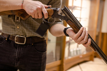 young man reload a rifle in guns store, man want to buy rifle for hunting. customer in weapons...