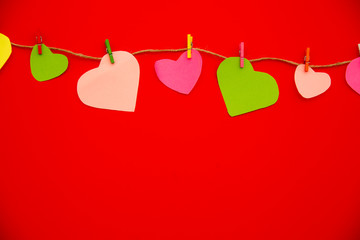 Hearts cut out of paper on clothespin, red color background