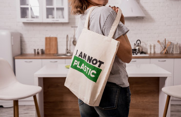 Young girl holding a cloth bag. At the kitchen. I am not plastic. 