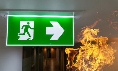 Green fire escape sign hang on the ceiling in the office.