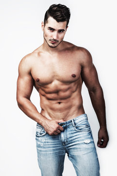 Male shirtless model with perfect body in jeans posing over white background. Close-up. Studio shot.
