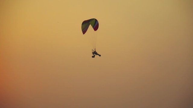 Paramotor gliding flying in the orange sky