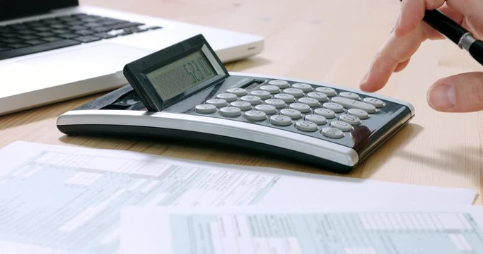 Closeup of US tax form 1040 and businessman hand calculating and filling report paper at the office. 4k footage resolution.
