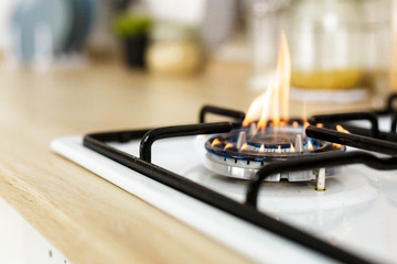 Macro closeup of modern luxury gas stove top with blue fire flame knobs bokeh blurry blurred background - obrazy, fototapety, plakaty