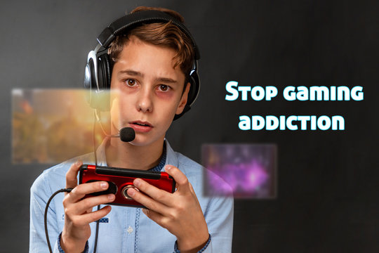 A tired teenager with black eyes listlessly plays a computer game with headphones. Transparent screens with games in front of the player. Dark background. The concept of dependence on online games