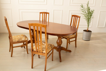 A classic set of wooden furniture for the kitchen. A set of chairs to the table in a classic interior