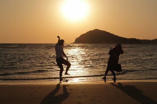 Couple are doing funny thing beautiful sunset background.