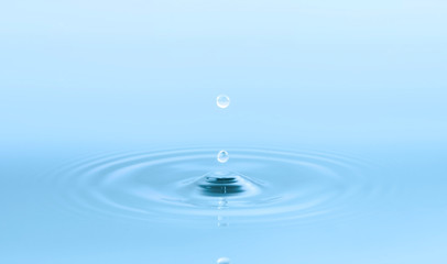 Two water drops and circle ripple, light blue water, close up