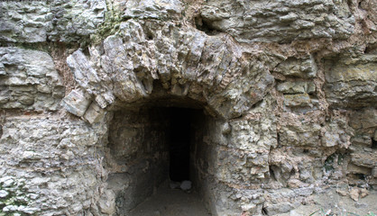 Fototapeta premium Window in an old medieval castle. Ruins, rough stone. Historical photography. The window is at ground level.