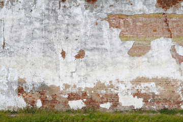 an exposed white stucco concrete and red brick garden wall with grass verge in the afternoon