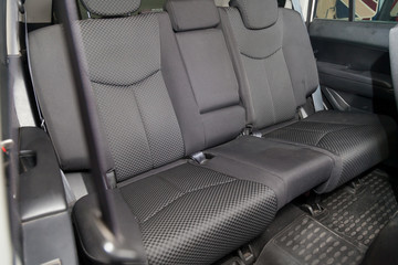 Close-up aon rear seats with velours fabric upholstery in the interior of an Korean car in black after dry cleaning with floor mat carpets. Auto service industry.