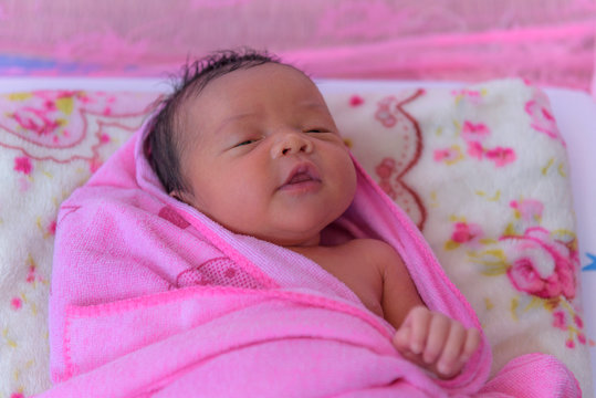Sleeping newborn baby in a wrap on white blanket. Beautiful portrait of little child girl 14days, two week old.