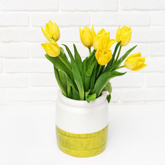 Spring flowers of tulip in vase on decorative brick wall.  Background for 8 March and Mother Womens Day. Gift for woman.