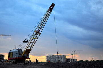 Fototapeta na wymiar Large crawler crane or dragline excavator with a heavy metal wrecking ball on a steel cable. Wrecking balls at construction sites. Dismantling and demolition of buildings and structures - Image