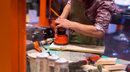 Female Worker grinds the wood of angular grinding machine