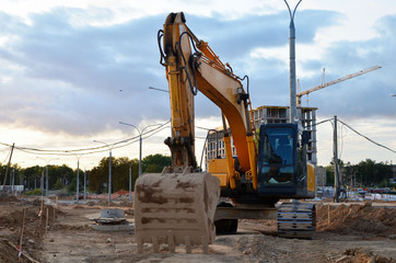 Excavator working at a construction site. Backhoe dig the ground for the foundation, laying storm...