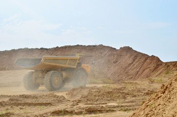 Obraz premium Big yellow dump trucks working in the open-pit. Transporting sand and minerals. Mining quarry for the production of crushed stone, sand and gravel for use in the construction industry - image