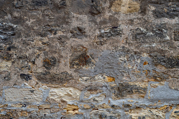 Old medieval wall made of mortar-fastened stones with traces of repair
