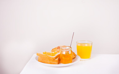 Bread toast with orange jam, glass of orange juice on the table. Breakfast concept.