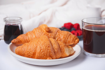 Fresh croissants buns, berries, black currant jam. Breakfast concept.