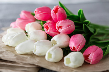 Fresh bouquet of white and pink tulips over recycled paper on gray background
