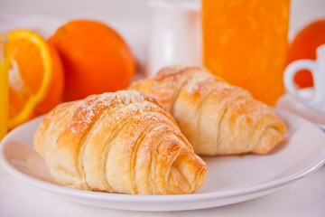 Fresh croissants buns, oranges, orange jam. Breakfast concept.
