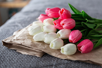 Fresh bouquet of white and pink tulips over recycled paper on gray background