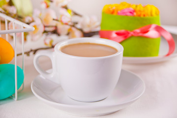 A cup of tea, small spring cake, flowers sakura, colorful eggs for Easter day. Spring concept.